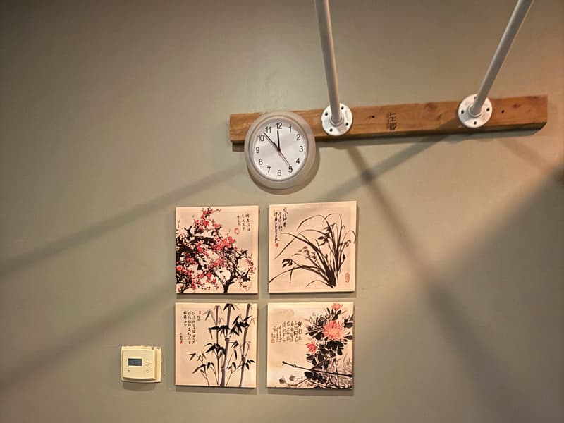 Treatment room wall with four ink-brush flower prints above the massage tables
