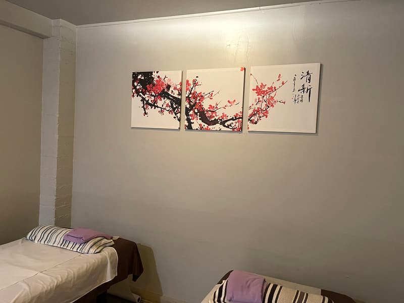 Couples treatment room with two massage tables, fresh white linens and cherry-blossom wall art